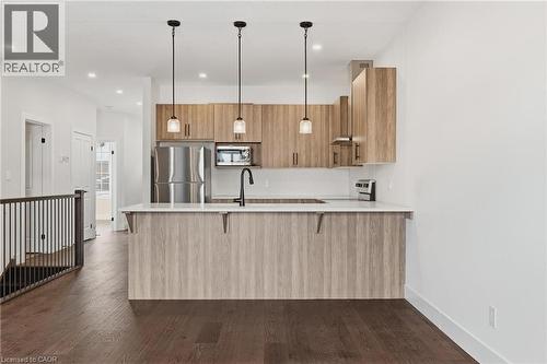 Kitchen with pendant lighting, a peninsula, stainless steel appliances, modern cabinets, and a breakfast bar - 4 Elgin Street W, Norwich, ON - Indoor Photo Showing Kitchen With Upgraded Kitchen
