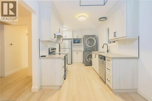 Kitchen with light countertops, appliances with stainless steel finishes, white cabinetry, and tasteful backsplash - 62 Harold Avenue Unit# Upper, Kitchener, ON - Indoor Photo Showing Laundry Room