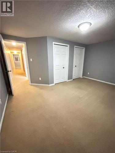 Unfurnished bedroom featuring light colored carpet, a closet, and a textured ceiling - 50 Howe Drive Unit# 12A, Kitchener, ON - Indoor Photo Showing Other Room