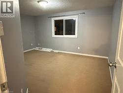 Carpeted spare room featuring a textured ceiling and baseboards - 