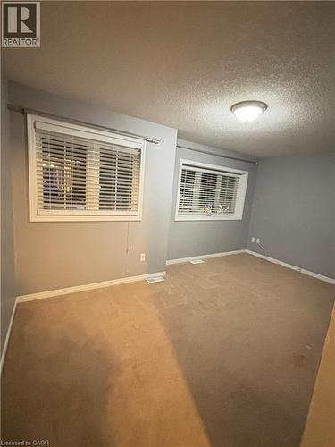 Carpeted spare room featuring a textured ceiling and baseboards - 50 Howe Drive Unit# 12A, Kitchener, ON - Indoor Photo Showing Other Room