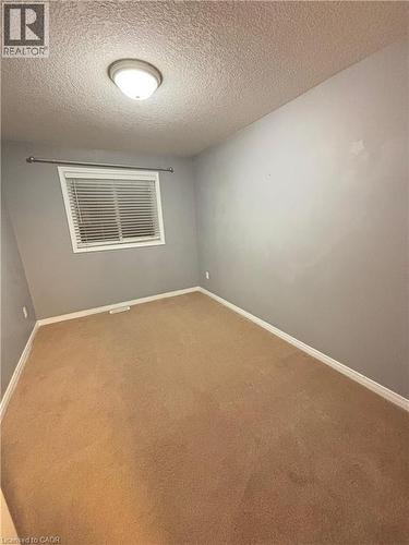 Carpeted empty room featuring a textured ceiling and baseboards - 50 Howe Drive Unit# 12A, Kitchener, ON - Indoor Photo Showing Other Room