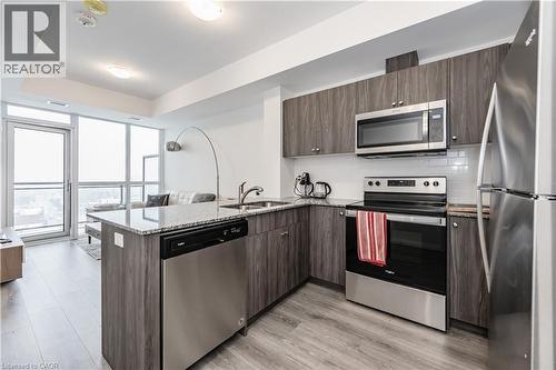 Kitchen with stainless steel appliances, a peninsula, light stone countertops, backsplash, and open floor plan - 60 Charles Street Unit# 2003, Kitchener, ON - Indoor Photo Showing Kitchen With Upgraded Kitchen