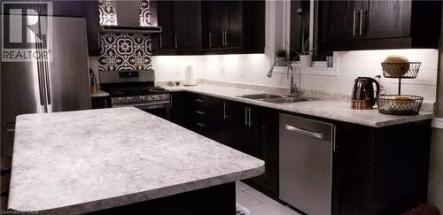 Kitchen with appliances with stainless steel finishes, light countertops, custom exhaust hood, light tile patterned floors, and backsplash - 118 Steeplechase Way, Waterloo, ON - Indoor Photo Showing Kitchen With Double Sink With Upgraded Kitchen