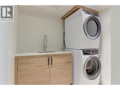 Stackable washer and dryer with a laundry sink for convenience - 761 Barnaby Road, Kelowna, BC - Indoor Photo Showing Laundry Room
