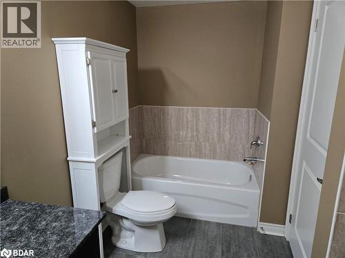Bathroom with vanity, toilet, a bathtub, and hardwood / wood-style floors - 33 Whitmer Street Unit# 324, Milton, ON - Indoor Photo Showing Bathroom