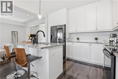 Kitchen featuring a breakfast bar, white cabinets, hanging light fixtures, an island with sink, and light stone counters - 592 Mayapple Street, Waterloo, ON - Indoor Photo Showing Kitchen With Upgraded Kitchen