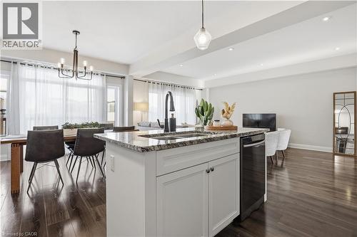 Kitchen with white cabinetry, light stone counters, decorative light fixtures, a center island with sink, and open floor plan - 592 Mayapple Street, Waterloo, ON - Indoor Photo Showing Kitchen With Upgraded Kitchen