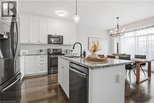 Kitchen featuring stainless steel appliances, light stone countertops, white cabinetry, a kitchen island with sink, and decorative light fixtures - 592 Mayapple Street, Waterloo, ON - Indoor Photo Showing Kitchen With Upgraded Kitchen