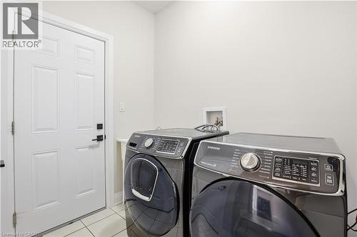 Laundry area featuring light tile patterned floors and separate washer and dryer - 592 Mayapple Street, Waterloo, ON - Indoor Photo Showing Laundry Room