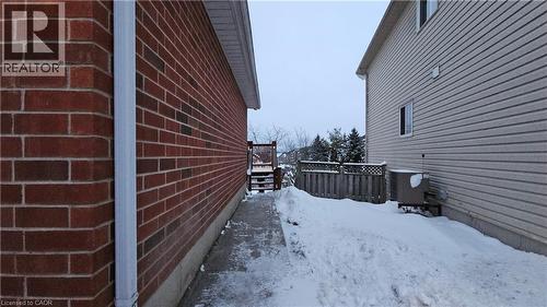 View of snow covered exterior with a wooden deck and brick siding - 10 Doll Court Unit# Lower, Kitchener, ON - Outdoor With Exterior