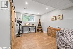 Bedroom with a barn door, light wood-style flooring, and recessed lighting - 