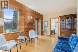 Living area featuring wood finished floors, wooden walls, and a baseboard heating unit - 