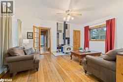 Living area with a wood stove, hardwood / wood-style floors, and a ceiling fan - 