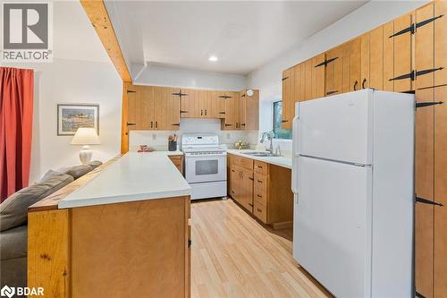 Kitchen with white appliances, light countertops, a peninsula, light wood-style flooring, and open floor plan - 9328 Wellington Road 50, Erin, ON - Indoor Photo Showing Kitchen With Double Sink