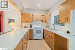 Kitchen with light wood-style flooring, white appliances, light countertops, recessed lighting, and brown cabinets - 
