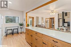 Kitchen featuring a wood stove, light countertops, light wood-style flooring, freestanding refrigerator, and open floor plan - 