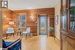Living area with healthy amount of natural light, light wood-style flooring, wood walls, and a baseboard heating unit - 