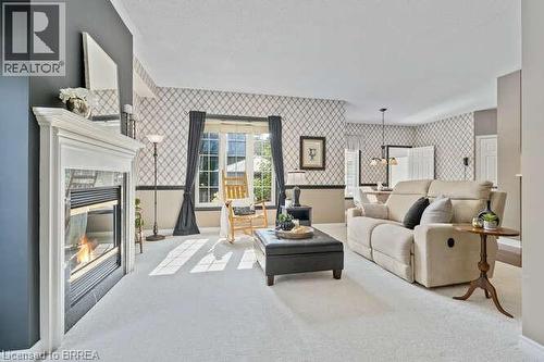Living area featuring wallpapered walls, carpet flooring, a chandelier, a premium fireplace, and a wainscoted wall - 119 Parkview Lane, Rockwood, ON - Indoor Photo Showing Living Room With Fireplace
