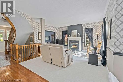 Living room featuring wallpapered walls, stairway, hardwood / wood-style flooring, and a glass covered fireplace - 119 Parkview Lane, Rockwood, ON - Indoor With Fireplace