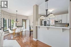 Kitchen featuring a breakfast bar area, white cabinets, wallpapered walls, appliances with stainless steel finishes, and light countertops - 