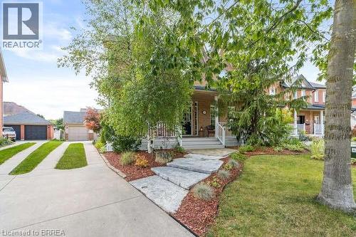View of property hidden behind natural elements featuring a front lawn, covered porch, a garage, and an outbuilding - 119 Parkview Lane, Rockwood, ON - Outdoor With Facade