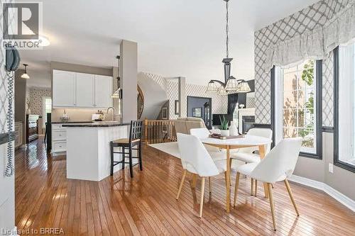 Dining room with light wood-type flooring, wallpapered walls, a chandelier, and a glass covered fireplace - 119 Parkview Lane, Rockwood, ON - Indoor Photo Showing Other Room