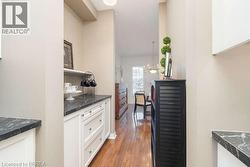 Corridor with dark wood finished floors and a chandelier - 