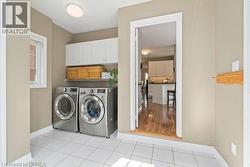 Laundry area with washing machine and dryer, cabinet space, and light tile patterned floors - 