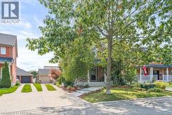 View of property hidden behind natural elements featuring covered porch, a front lawn, and a detached garage - 