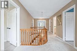 Hall with an upstairs landing, light carpet, and a chandelier - 