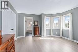 Unfurnished bedroom with light wood-type flooring, multiple windows, and connected bathroom - 