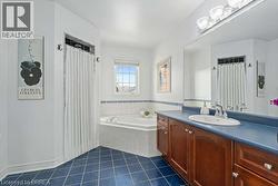 Full bath featuring a garden tub, vanity, a shower with shower curtain, and dark tile patterned floors - 
