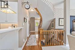 Hallway with an upstairs landing, light wood-type flooring, and vaulted ceiling - 
