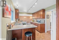 Kitchen featuring brown cabinets, tasteful backsplash, a breakfast bar, light countertops, and white appliances - 