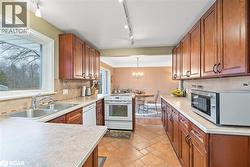 Kitchen featuring brown cabinets, white appliances, healthy amount of natural light, and light countertops - 