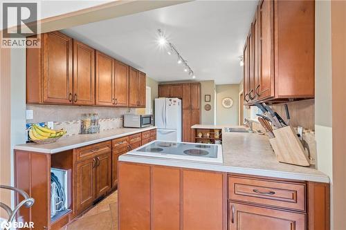Kitchen featuring brown cabinetry, light countertops, a peninsula, backsplash, and white appliances - 11317 Regional Road 25, Halton Hills, ON - Indoor Photo Showing Kitchen