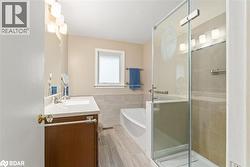 Full bath featuring vanity, a stall shower, a garden tub, and tile walls - 