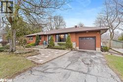 Ranch-style house featuring brick siding, driveway, a garage, a front yard, and a shingled roof - 