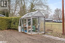 View of greenhouse featuring a fenced backyard and a sunroom - 