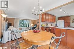 Dining room featuring light wood-style floors, a chandelier, rail lighting, and a fireplace - 
