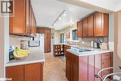 Kitchen featuring backsplash, brown cabinetry, light countertops, and rail lighting - 