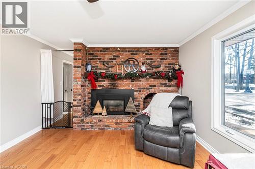 Living room featuring wood-type flooring, a brick fireplace, and ornamental molding - 7087 Rainham Road, Dunnville, ON - Indoor Photo Showing Living Room With Fireplace