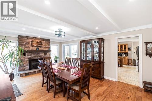Dining space with beam ceiling, light wood-style flooring, a stone fireplace, and recessed lighting - 7087 Rainham Road, Dunnville, ON - Indoor Photo Showing Dining Room With Fireplace