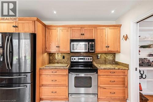 Kitchen featuring appliances with stainless steel finishes, light stone counters, and tasteful backsplash - 7087 Rainham Road, Dunnville, ON - Indoor Photo Showing Kitchen