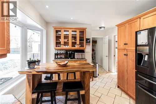 Kitchen featuring black fridge, glass insert cabinets, brown cabinets, light tile patterned floors, and recessed lighting - 7087 Rainham Road, Dunnville, ON - Indoor