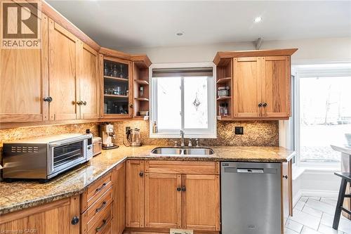 Kitchen featuring stainless steel dishwasher, open shelves, light stone countertops, backsplash, and light tile patterned floors - 7087 Rainham Road, Dunnville, ON - Indoor Photo Showing Kitchen With Double Sink