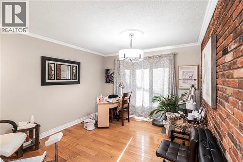 Office space with light wood-style flooring, ornamental molding, a textured ceiling, and brick wall - 7087 Rainham Road, Dunnville, ON - Indoor