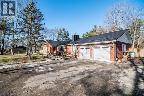 View of front of property with a metal roof, a chimney, brick siding, driveway, and an attached garage - 7087 Rainham Road, Dunnville, ON - Outdoor