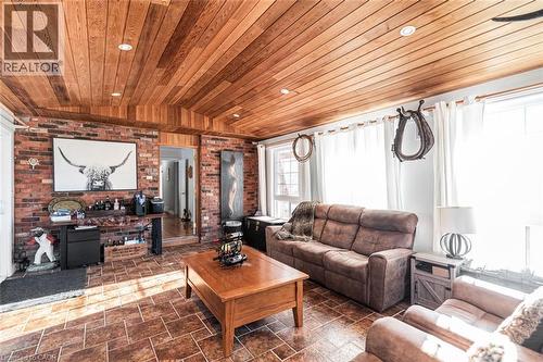 Living area with vaulted ceiling, brick wall, wood ceiling, and stone tile flooring - 7087 Rainham Road, Dunnville, ON - Indoor Photo Showing Living Room